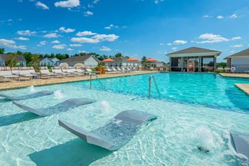a large swimming pool with chairs in front of a building